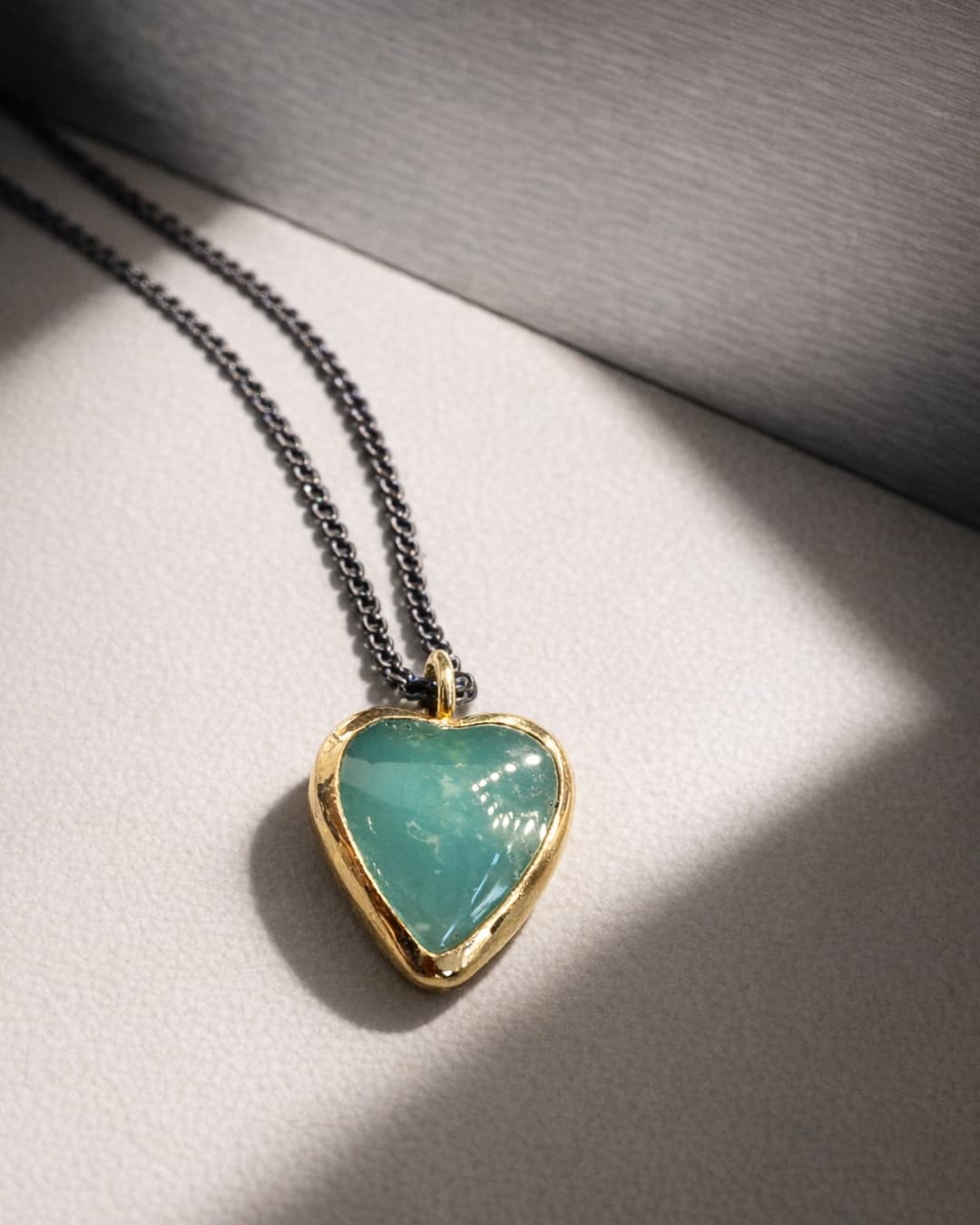 The same heart pendant, upscaled and restyled on pale leather with directional light